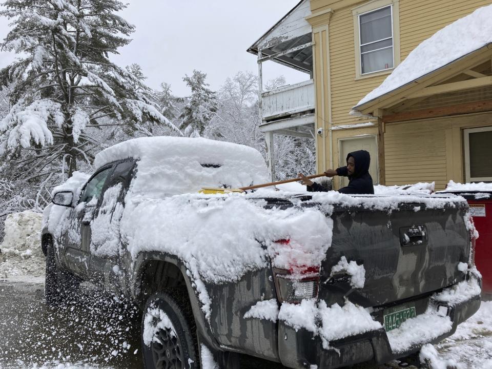 Jack Whalen brushes snow off his truck with a push broom in Marshfield, Vt., Tuesday, March 14. 2023. (AP Photo/Lisa Rathke)