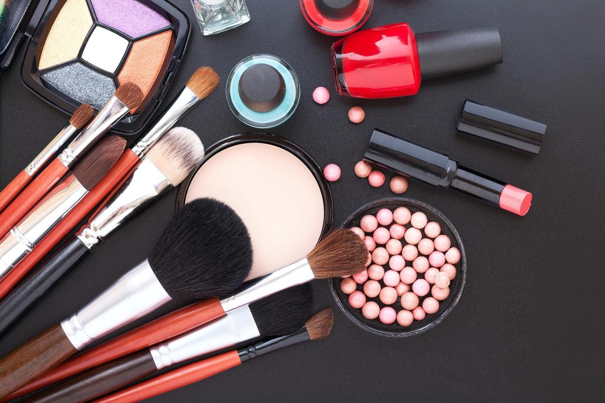 Makeup brushes and makeup spread on a black table