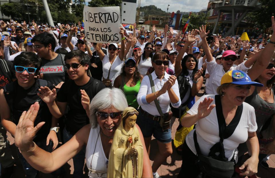 Opposition demonstrators, one holding a statue of the Virgin Mary, and another holding a sign that reads in Spanish "Freedom for the prisoners," protest in Caracas, Venezuela, Saturday, Feb. 15, 2014. Demonstrators are protesting the Wednesday killings of two university students who were shot in different incidents following an anti-government protest demanding the release of student protesters arrested in various parts of the country. (AP Photo/Fernando Llano)