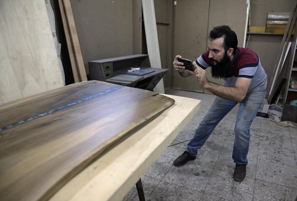 Ali Hedieloo takes a photo of his product to post on social media at his furniture workshop in the southern suburbs of Tehran, Iran, Friday, July 30, 2021. New legislation proposed by Iran's hard-line lawmakers that is designed to restrict access to social media applications in Iran has sent a wave of panic through society, stirring concerns among young Iranians, social media users and business owners. Like an estimated 1 million other Iranians, Hedieloo uses social media to find customers. (AP Photo/Vahid Salemi)