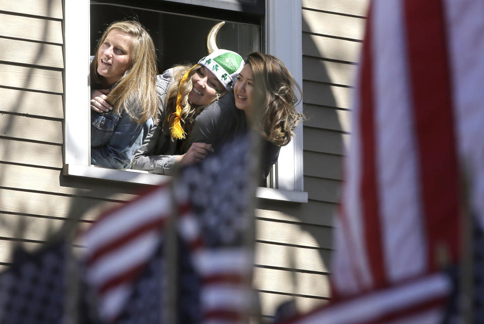Spectators watch from a window during the annual St. Patrick's Day parade, Sunday, March 17, 2019, in Boston's South Boston neighborhood. The city celebrated the holiday with crowds lining the route of the 118th edition of the parade. (AP Photo/Steven Senne)