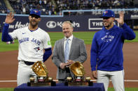 Toronto Blue Jays' Kevin Kiermaier, left, and teammate Jose Berrios, right, pose for a photo with their golden glove awards presented by Steve Cohen, center, director of pro baseball services at Rawlings, during a ceremony prior to a baseball game against the Colorado Rockies in Toronto, Friday, April 12, 2024. (Frank Gunn/The Canadian Press via AP)