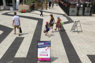 People pass by the sign of a COVID-19 immunization clinic in downtown Toronto, Canada, on Sunday, July 18, 2021. With nearly 70% of its adult population receiving at least one dose of a COVID-19 vaccine, Canada has the world's highest vaccination rate and is now moving on to immunize children, who are at far lower risk of coronavirus complications and death. (AP Photo/Kamran Jebreili)