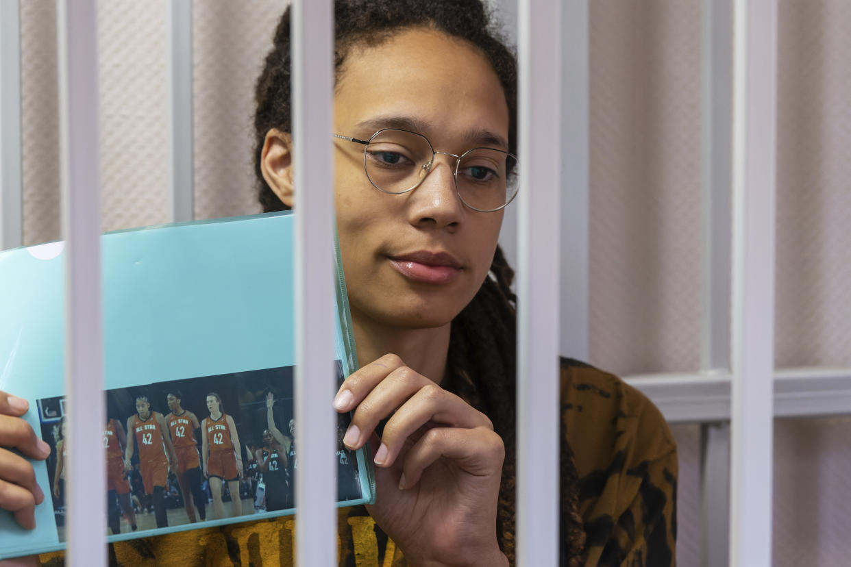 La estrella de la WNBA y dos veces medallista de oro olímpica Brittney Griner sostiene una foto de las jugadoras del reciente All Star Game con su número. La jugadora aparece sentada en una sala enrejada del tribunal antes de una audiencia en las afueras de Moscú, Rusia. (Foto