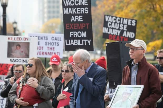 Ted Kuntz (centre), director and vice president of Vaccine Choice Canada, joins fellow protesters in observing a minute's silence during a rally against Ontario's vaccination law outside the legislature in Toronto on Oct. 29, 2019. (Chris Young/The Canadian Press - image credit)