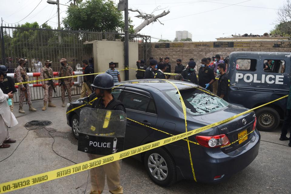 EDITORS NOTE: Graphic content / Policemen guard a car used by alleged gunmen outside the Pakistan Stock Exchange building in Karachi on June 29, 2020. - At least six people were killed when gunmen attacked the Pakistan Stock Exchange in Karachi on June 29, with a policeman among the dead after the assailants opened fire and hurled a grenade at the trading floor, police said. (Photo by Rizwan TABASSUM / AFP) (Photo by RIZWAN TABASSUM/AFP via Getty Images)