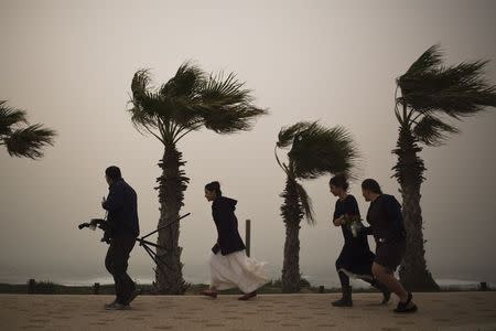 A bride (2nd L) and her friends walk behind a photographer as they brave the wind on the shore of the Mediterranean sea in the southern city of Ashkelon January 6, 2015. REUTERS/Amir Cohen