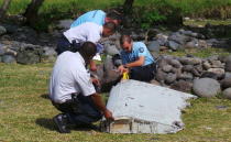 French gendarmes and police inspect a large piece of plane debris which was found on the beach in Saint-Andre, on the French Indian Ocean island of La Reunion, July 29, 2015. REUTERS/Zinfos974/Prisca Bigot