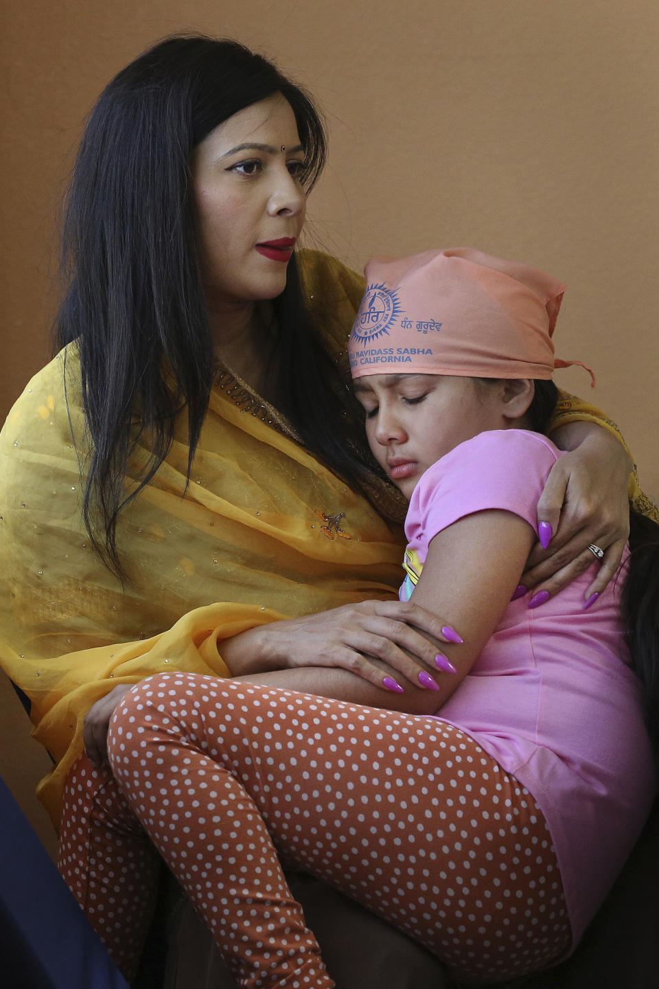 Renu Bhatti tends to her daughter Naina, who was feeling ill, after a meal during the Shri Guru Ravidass Sabha ceremony at the Shri Guru Ravidass Sabha ceremony at a temple in Fresno, Calif. Sunday, May 7, 2023. Members of the Ravidassia community in California are followers of Guru Ravidass, a 14th century Indian guru of a caste formerly considered untouchable. The Ravidassia community statewide is advocating for new legislation to outlaw caste-based discrimination. (AP Photo/Gary Kazanjian)