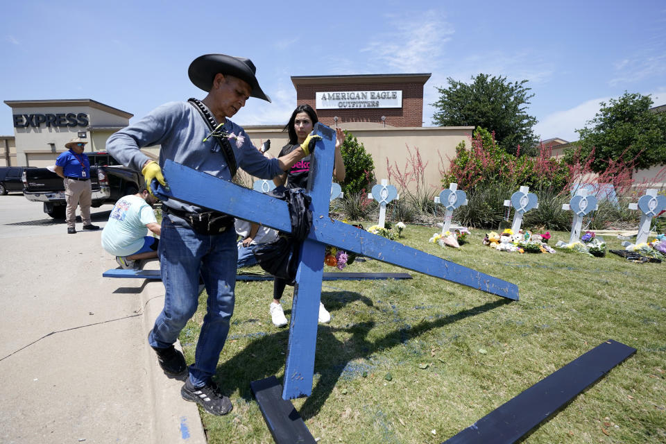 Roberto Marquez, left, and Lenna Maleki, center, work on constructing and painting a large cross at a makeshift memorial by the mall where several people were killed several days earlier, Monday, May 8, 2023, in Allen, Texas. (AP Photo/Tony Gutierrez)