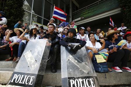 Anti-government protesters sit with riot policemen outside the National Broadcast Services of Thailand (NBT) television station in Bangkok May 9, 2014. REUTERS/Athit Perawongmetha