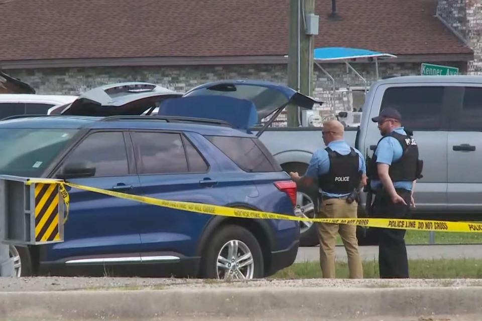 <p>WWLTV/Youtube</p> Police officers standing by a vehicle near crime scene tape