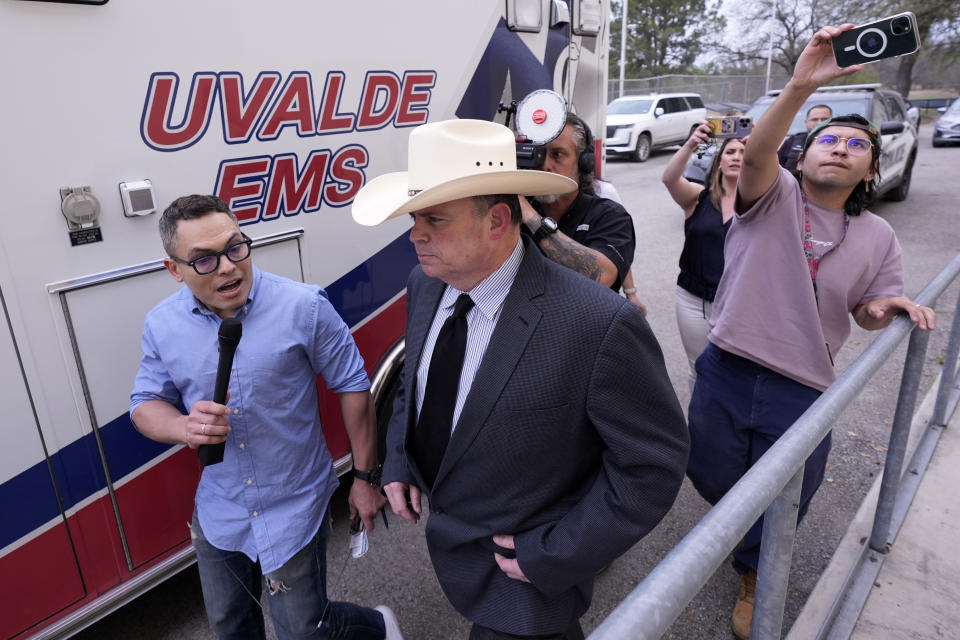 Jesse Prado, center in cowboy hat, an Austin-based investigator, is pursued by the media after he shared his findings at a special city council meeting in Uvalde, Texas, Thursday, March 7, 2024. (AP Photo/Eric Gay)