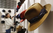 A woman looks at hats in a Borsalino store in downtown Milan, Italy, Wednesday, Jan. 16, 2019. If the traditional Italian hat-maker Borsalino was once synonymous with the fedora, its new private equity owners want to imbue the brand with cachet that extends to couture, sportswear and streetwear for women and Millennials -- without alienating its classic customers and the silhouette that helped shape the rough-and-tumble images of Robert Redford, Frank Sinatra and, perhaps no one more than, Humphrey Bogart. (AP Photo/Antonio Calanni)