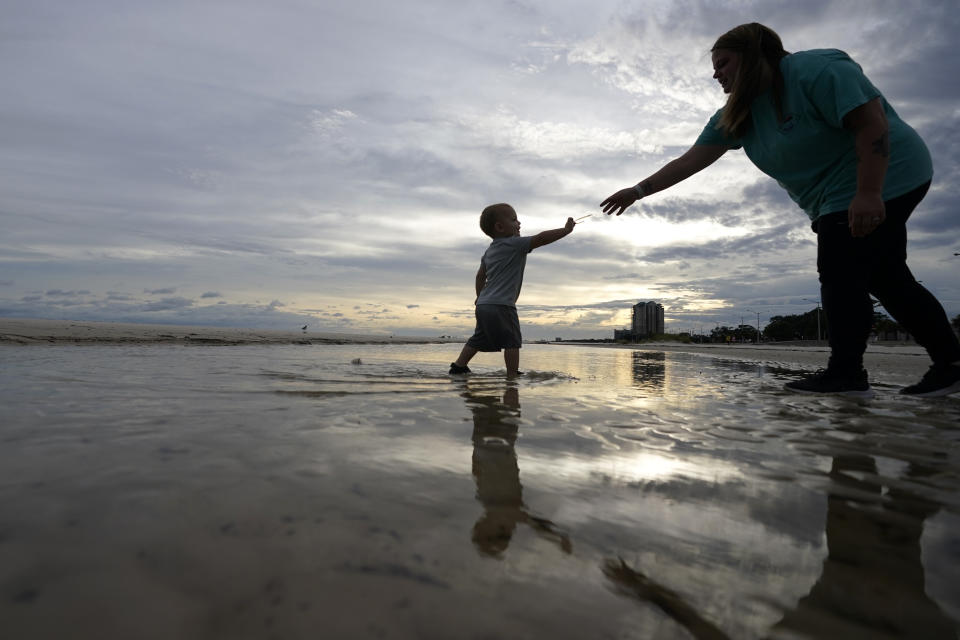 Nikita Pero de Gulfport, Mississippi, camina con su hijo Vinny Pero, de 2 años, por la playa en el Golfo de México, en Biloxi, Mississippi, el lunes 14 de septiembre de 2020. (AP Foto/Gerald Herbert)
