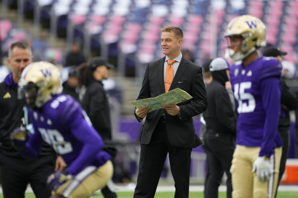 Former NFL and Washington quarterback Brock Huard, center, holds his notes as he watches warmups on the field before an NCAA college football game between Washington and Utah, Saturday, Nov. 11, 2023, in Seattle. The final football season for the Pac-12 with its current membership is coming to a thrilling conclusion. The conference wraps up regular-season play this week before the title game in Las Vegas on Dec. 1, 2023. Washington and Oregon still have hopes of getting the Pac-12 its first College Football Playoff berth since 2016. (AP Photo/Lindsey Wasson)
