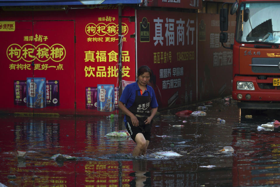 Xing, a shop owner at Yubei Agricultural and Aquatic Products World, walks in floodwaters at the market in Xinxiang in central China's Henan Province, Monday, July 26, 2021. Record rain in Xinxiang last week left the produce and seafood market soaked in water. Dozens of people died in the floods that immersed large swaths of central China's Henan province in water. (AP Photo/Dake Kang)