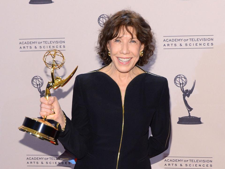 Lily Tomlin holds an Emmy award.