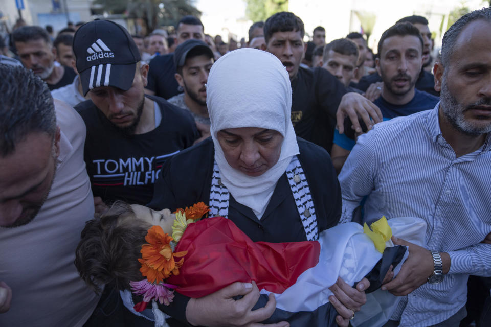 Ramallah governor Laila Ghannam, with a white scarf, carries the body of 2 1/2 year old Palestinian toddler Mohammed al-Tamimi upon his arrival at the Palestine Medical Complex, in the West Bank city of Ramallah, Monday, June 5, 2023. The Palestinian toddler who was shot by Israeli troops in the occupied West Bank last week died of his wounds on Monday, Israeli hospital officials said. (AP Photo/Nasser Nasser)