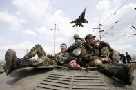 A fighter jet flies above as Ukrainian soldiers sit on an armoured personnel carrier in Kramatorsk, in eastern Ukraine April 16, 2014. Ukrainian government forces and separatist pro-Russian militia staged rival shows of force in eastern Ukraine on Wednesday amid escalating rhetoric on the eve of crucial four-power talks in Geneva on the former Soviet country's future. REUTERS/Marko Djurica (UKRAINE - Tags: POLITICS CIVIL UNREST MILITARY TPX IMAGES OF THE DAY)