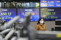 A currency trader walks by the screens showing the Korea Composite Stock Price Index (KOSPI), left, and the foreign exchange rate between U.S. dollar and South Korean won at a foreign exchange dealing room in Seoul, South Korea, Tuesday, June 7, 2022. Asian stock markets were mixed Tuesday following a bond sell-off on Wall Street amid anxiety about higher U.S. interest rates.(AP Photo/Lee Jin-man)