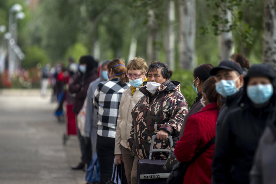 People line up as they wait to receive a ration of donated food for people at risk of social exclusion by volunteers from Aluche neighborhood association, in Madrid, Spain, Saturday, May 16, 2020. Aluche Neighborhood association warn that the economic crisis caused by coronavirus has left many out of resources. Spain has been in lockdown to fight the coronavirus pandemic. (AP Photo/Manu Fernandez)