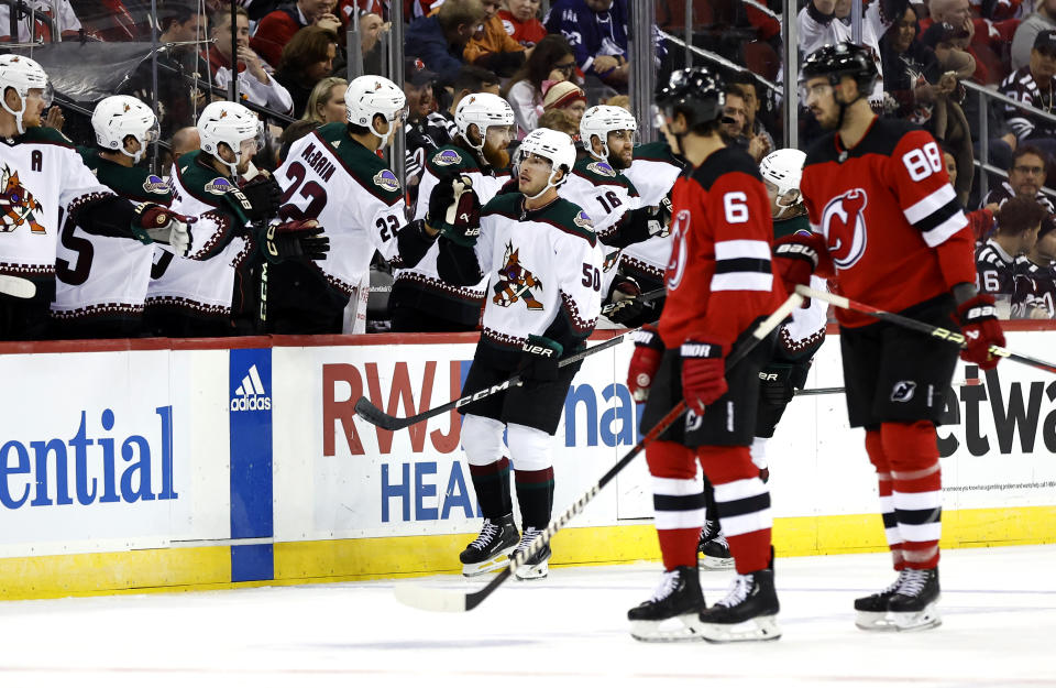 Arizona Coyotes defenseman Sean Durzi (50) celebrates with teammates after scoring a goal against the New Jersey Devils during the second period of an NHL hockey game Friday, Oct. 13, 2023, in Newark, N.J. (AP Photo/Noah K. Murray)