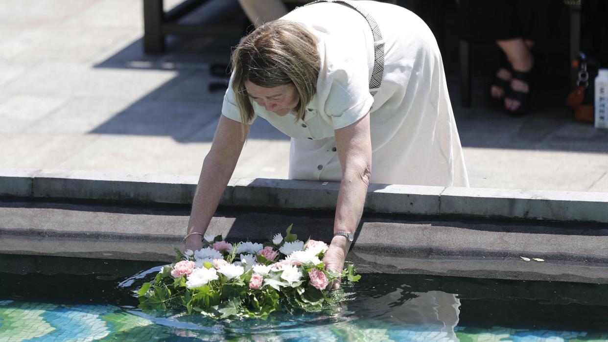 A woman lays a wreath at the Stardust commemoration