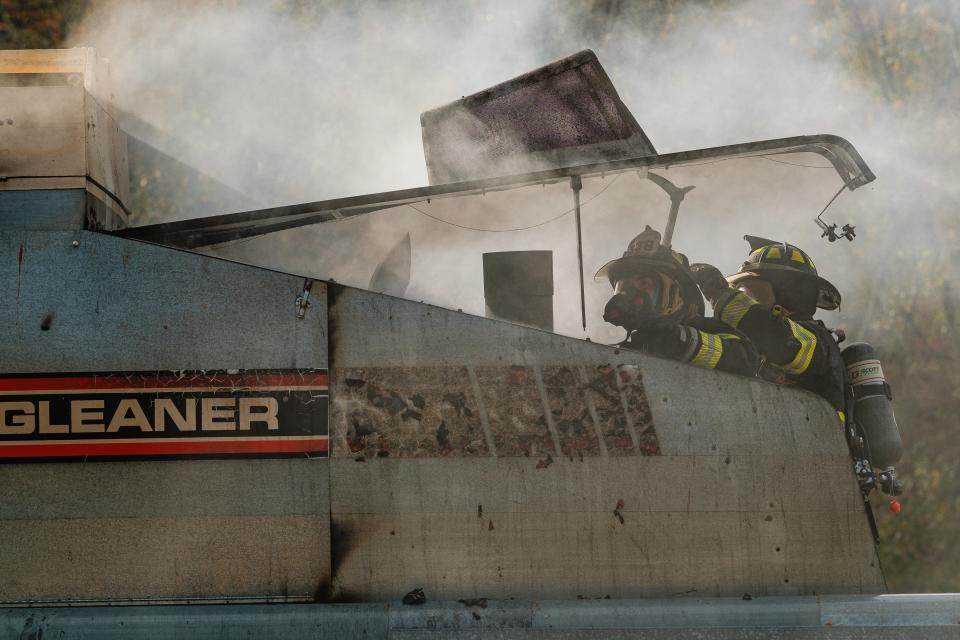 Firefighters from Bolivar Fire Department work to safely prop open the rear compartment of a harvester that caught fire while operating in a soybean field, Wednesday, Oct. 25 in Lawrence Township.