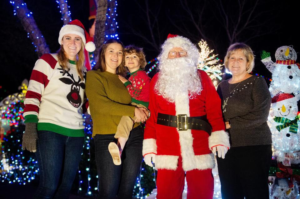 Lindsey Rowe, from left, Lauren Rowe-Hobbs, Hollis Hobbs and Sheri Rowe pose for photograph with Santa near the Christmas lights on Indian Pines Lane in Madison, Miss., Tuesday, Dec. 21, 2021. The family has set up the holiday lights display at their home for nearly 30 years.