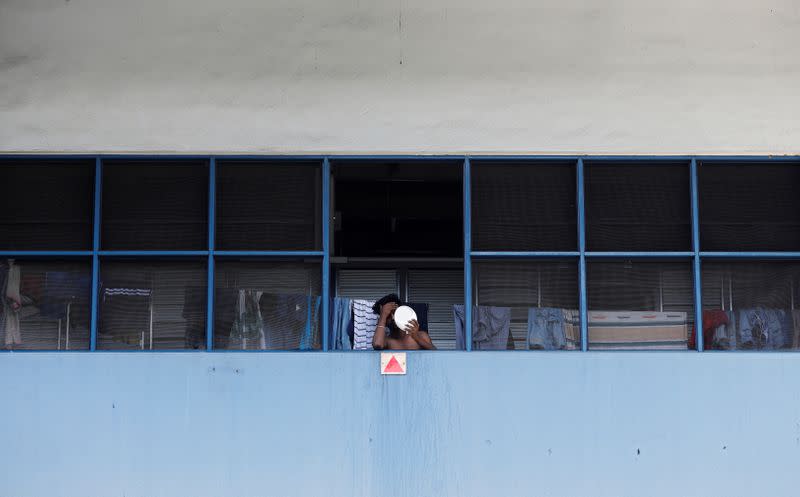 A migrant worker living in a factory-converted dormitory looks into a mirror as he serves stay-home notice during the coronavirus disease (COVID-19) outbreak in Singapore