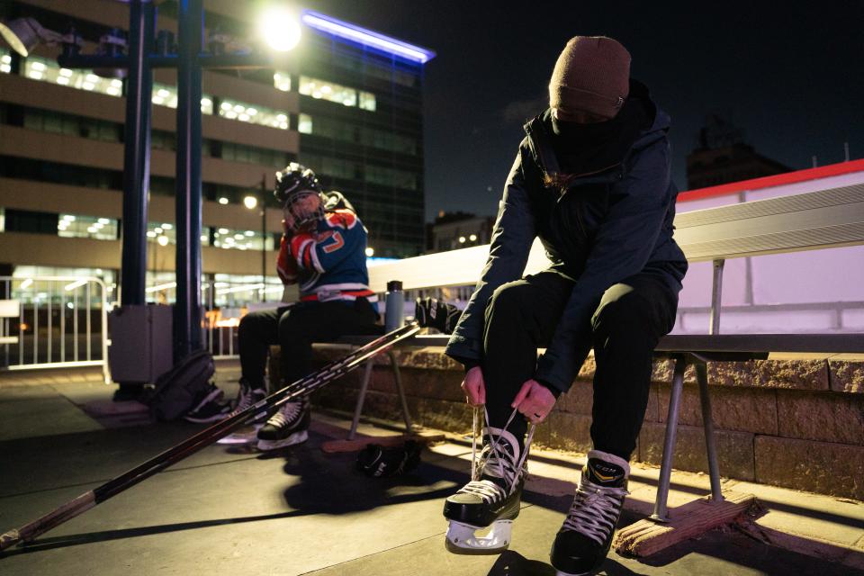 Kylee Fine, right, tightens up her ice skates as Valerie Jinenez adjusts her helmet as the two prepare to play pond hockey Monday night.