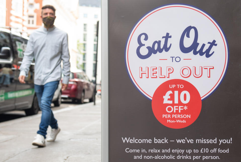 File photo dated 3/8/2020 of a man passing a sign advertising the 'Eat Out to Help Out' scheme. Three men have been arrested on suspicion of fraud relating to the Eat Out to Help Out discount scheme, HM Revenue and Customs (HMRC) has said.