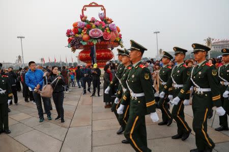 Paramilitary policemen march as people attend a flag-raising ceremony at Tiananmen Square a day before the 19th National Congress of the Communist Party of China begins in Beijing, China, October 17, 2017. REUTERS/Damir Sagolj