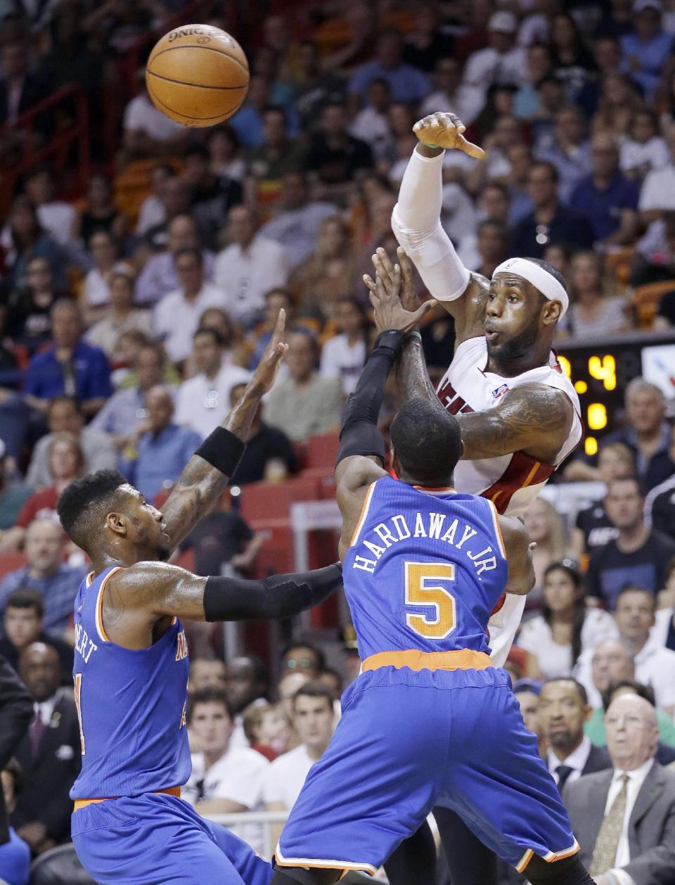 Miami Heat forward LeBron James passes past New York Knicks guard Iman Shumpert, left, and guard Tim Hardaway Jr. (5) during the first half of an NBA basketball game, Sunday, April 6, 2014, in Miami. (AP Photo/Wilfredo Lee)