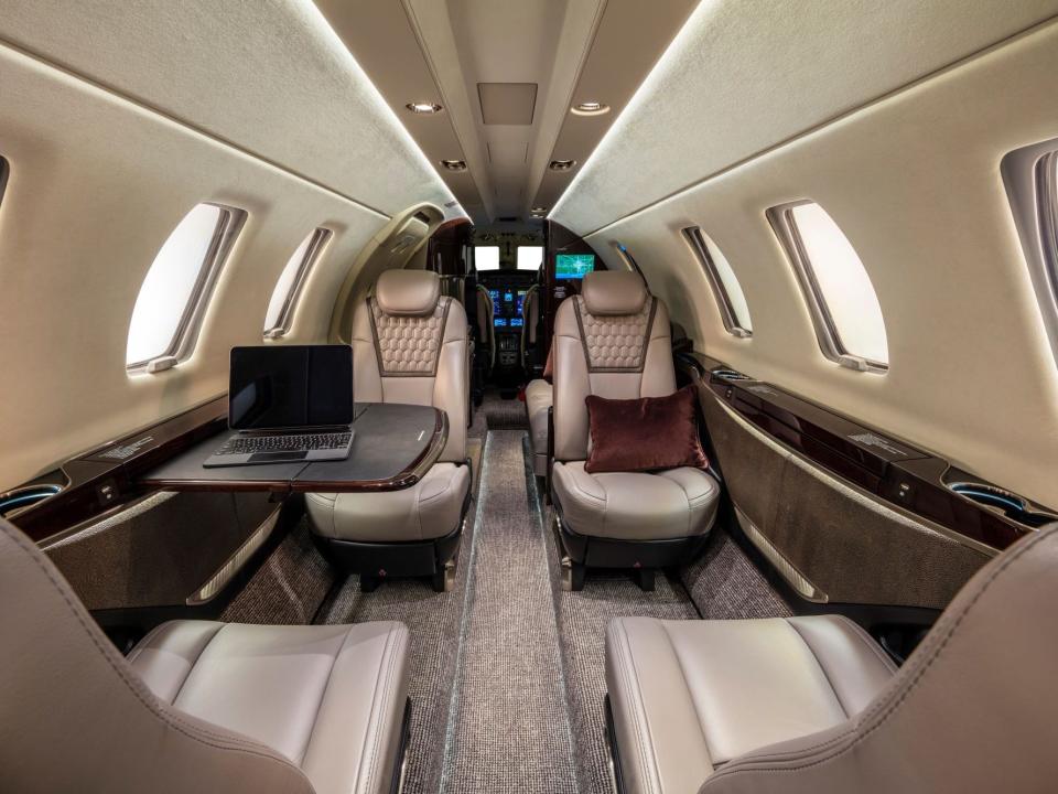 The beige interior of the CJ4 with a laptop on the folded out table.