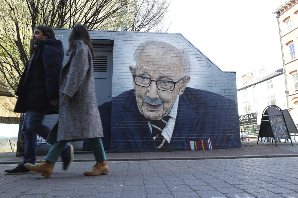 People walk past a mural of Captain Tom Moore by by street artist Akse P19 in Manchester's North Quarter, England, Friday April 2, 2021. (Peter Byrne/PA via AP)