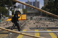 People walk by a road scattered with bricks and barricades by pro-democracy protesters outside the Hong Kong Baptist University, in Hong Kong, Wednesday, Nov. 13, 2019. Police increased security around Hong Kong and its university campuses as they brace for more violence after sharp clashes overnight with anti-government protesters. (AP Photo/Vincent Yu)