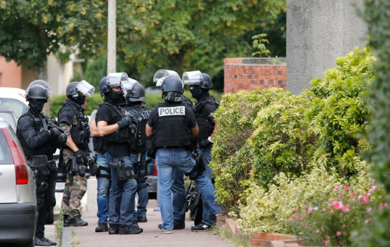 Policemen stand in a street during the search of a house in the Normandy village of Saint-Etienne du Rouvray on July 26, 2016, following a church attack in which a priest was killed