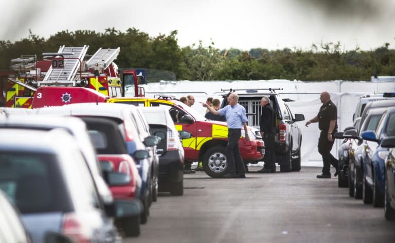 Members of the emergency services attend the scene where a private jet crashed at a car auction site next to Blackbushe Airport in Hampshire, southern England on August 1, 2015