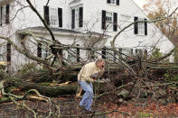 John Constantine makes his way out of his house after winds from Hurricane Sandy toppled a tree fell onto it in Andover, Mass. Monday, Oct. 29, 2012. Hurricane Sandy continued on its path Monday, as the storm forced the shutdown of mass transit, schools and financial markets, sending coastal residents fleeing, and threatening a dangerous mix of high winds and soaking rain. (AP Photo/Winslow Townson)