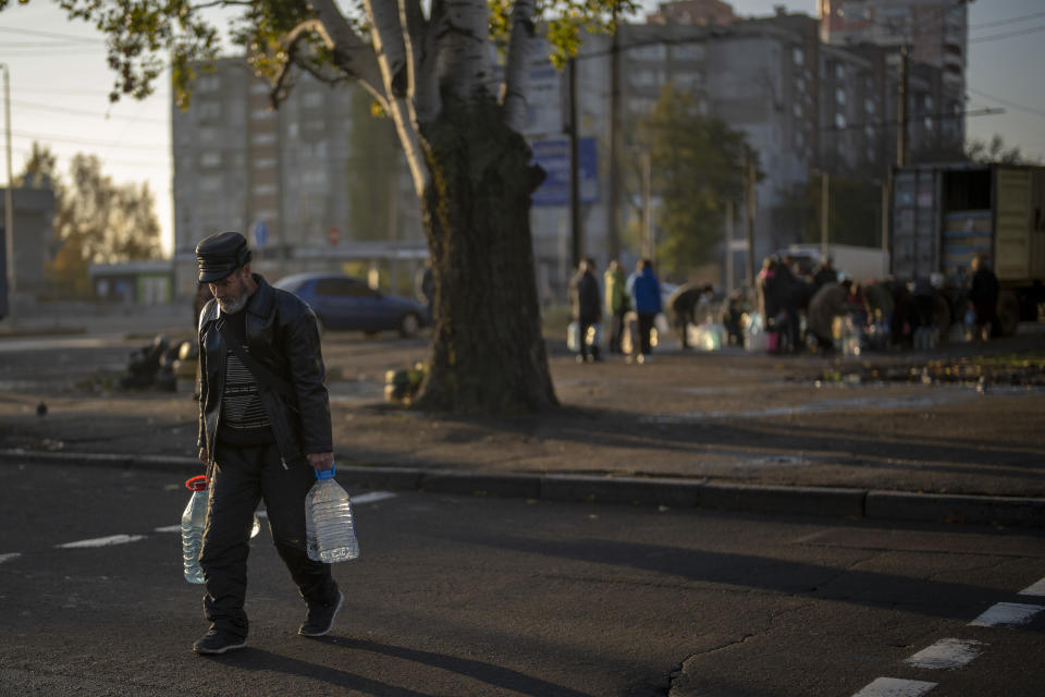 A man carries plastic bottles after refilling them in a tank, in the center of Mykolaiv, Monday, Oct. 24, 2022. Since mid-April, citizens of Mykolaiv, with a pre-war population of half a million people, have lived without a centralized drinking water supply. Russian Forces cut off the pipeline through which the city received drinking water for the last 40 years. (AP Photo/Emilio Morenatti)