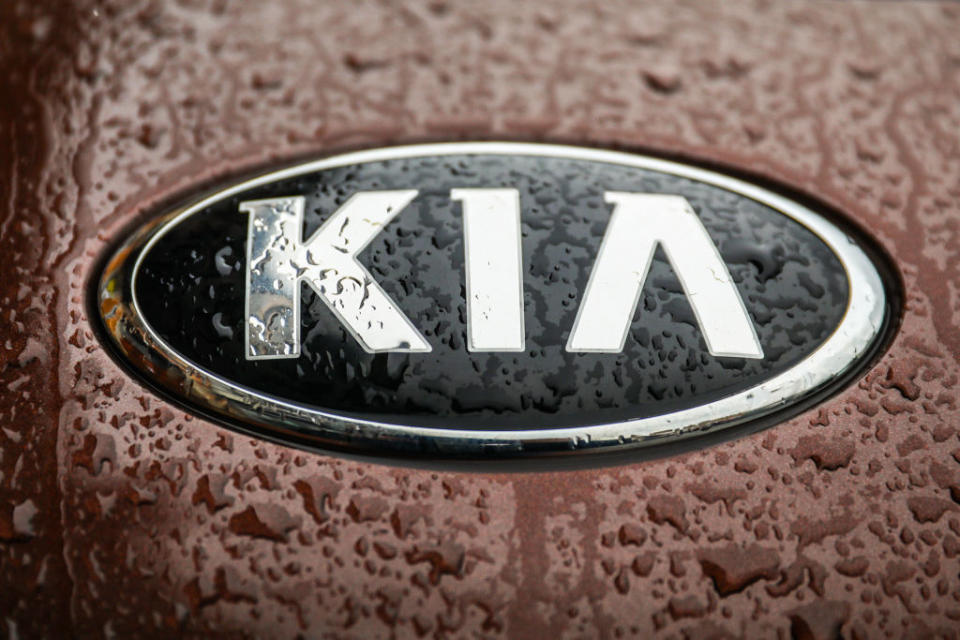 A Kia car emblem is covered with raindrops.