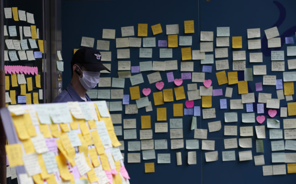 A security man stands near the condolence messages for late Seoul Mayor Park Won-soon in front of Seoul City Hall where official funeral is held in Seoul, South Korea, Monday, July 13, 2020. Masked mourners gave speeches and laid flowers before the coffin of Seoul's mayor during his funeral Monday, while a live broadcast online drew a mixture of condolence messages and insults. (AP Photo/Lee Jin-man)