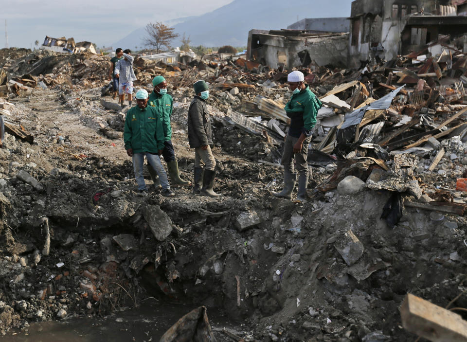 In this Oct. 2, 2018 photo, volunteers of the humanitarian wing of the Islamic Defenders Front examine the damage caused by the earthquake and liquefaction at Balaroa neighborhood in Palu, Central Sulawesi, Indonesia Indonesia. Indonesia's Islamic Defenders Front is better known for vigilante actions against gays, Christmas decorations and prostitution, but over the past decade and a half it has repurposed its militia into a force that's as adept at searching for victims buried under earthquake rubble and distributing aid as it is at inspiring fear. (AP Photo/Dita Alangkara)