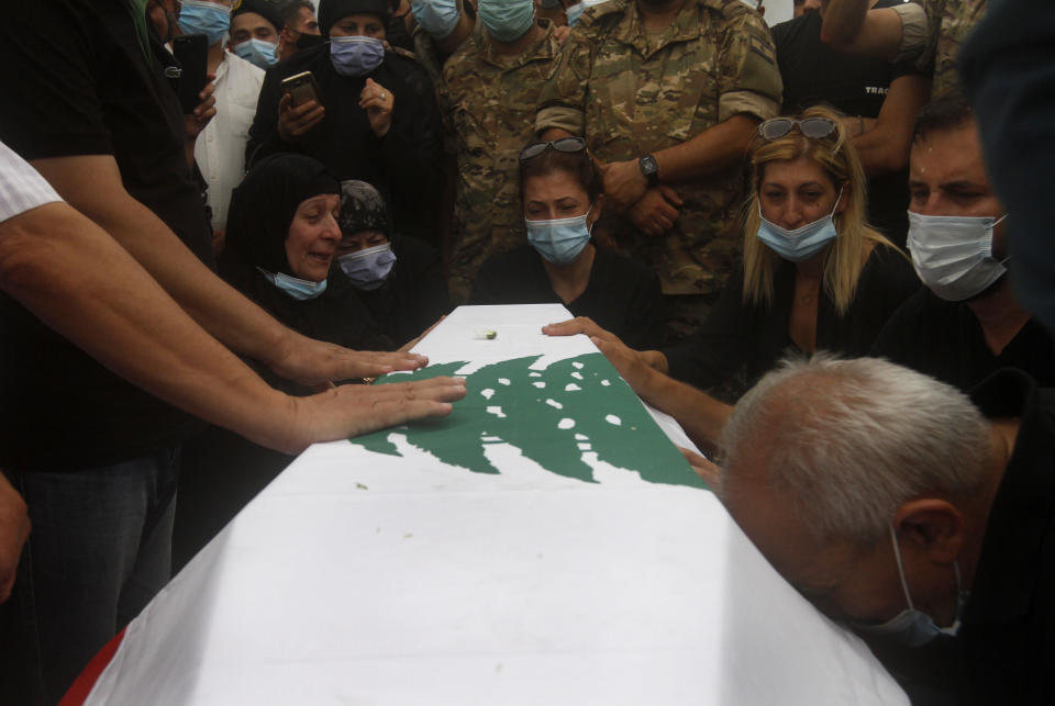 Relatives of Lebanese army lieutenant Ayman Noureddine, who was killed by Tuesday's explosion that hit the seaport of Beirut, mourn over his coffin during his funeral procession, in Numeiriyeh village, south Lebanon, Friday, Aug. 7, 2020. Rescue teams were still searching the rubble of Beirut's port for bodies on Friday, nearly three days after a massive explosion sent a wave of destruction through Lebanon's capital. (AP Photo/Mohammed Zaatari)