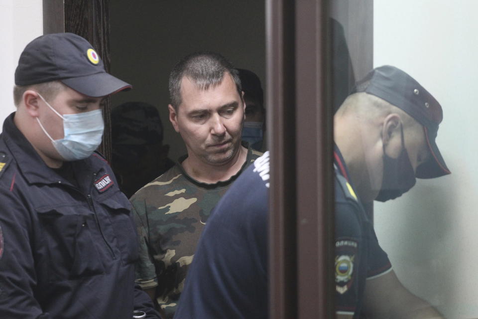 Alexander Popov, a man who was arrested on suspicion of murder and surrounded by police officers, arrives at a courtroom in the city of Gorodets, 60 km. (36 miles) north-west of Nizhny Novgorod, Russia, Sunday, June 20, 2021. A court in central Russia has arraigned the suspect on murder charges in the death of an American woman studying at a local university. The body of 34-year-old Catherine Serou was found Saturday in the woods area near the city of Nizhny Novgorod, 400 kilometers (250 miles) east of Moscow. (AP Photo/Roman Yarovitsyn)