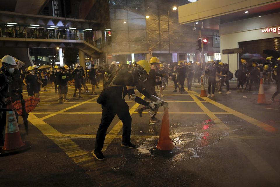 A protester uses a traffic cone to cover a tear gas canister which fired by riot police during a protest in Hong Kong, Sunday, July 28, 2019. Police fired tear gas at protesters in Hong Kong on Sunday for the second night in a row in another escalation of weeks-long pro-democracy protests in the semi-autonomous Chinese territory. (AP Photo/Vincent Yu)