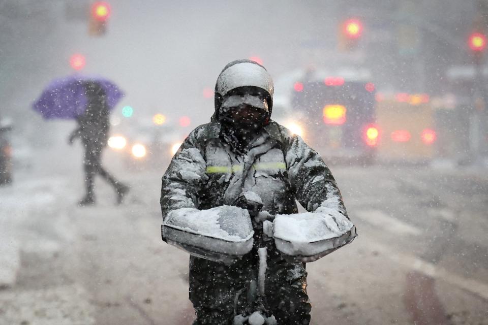 A delivery worker rides a bicycle on East 125th Street in heavy snowfall (REUTERS)
