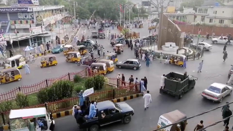 Taliban militants waving a Taliban flag on the back of a pickup truck drive past a crowded street at Pashtunistan Square area in Jalalabad, Afghanistan in this still image taken from social media video uploaded on August 15, 2021. Social media website/via REUTERS THIS IMAGE HAS BEEN SUPPLIED BY A THIRD PARTY.